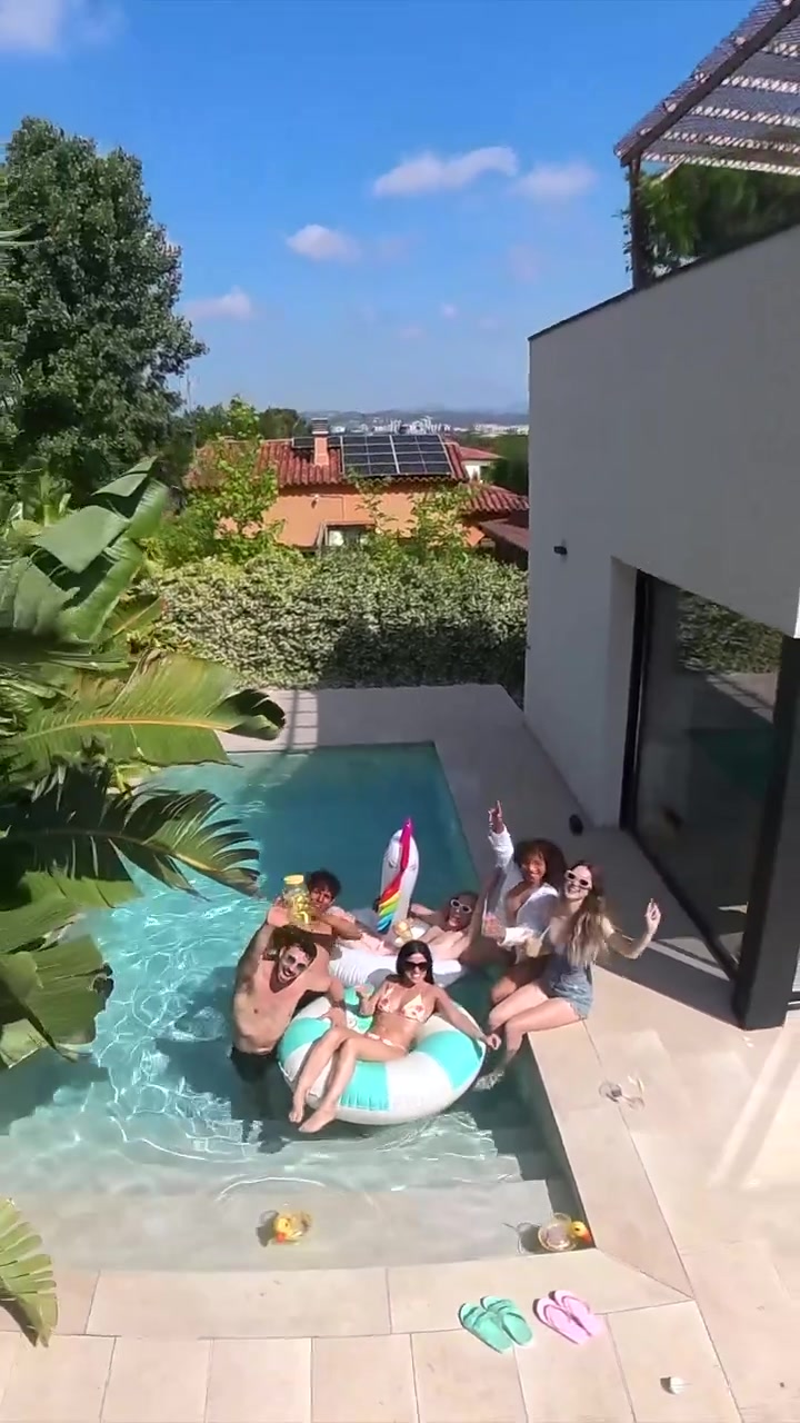 Gruppo di amici felici che salutano e posano a una festa in piscina soleggiata.