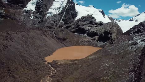 antena, reversa, drone disparó lejos de un lago de agua marrón debajo de picos montañosos nevados, en la región de cusco, andes, perú
