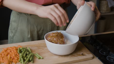 woman cooking chicken and vegetables in the kitchen