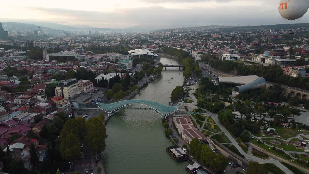 Letecký pohled na Tbilisi s řekou Kura, která se vine budovami a mosty dole