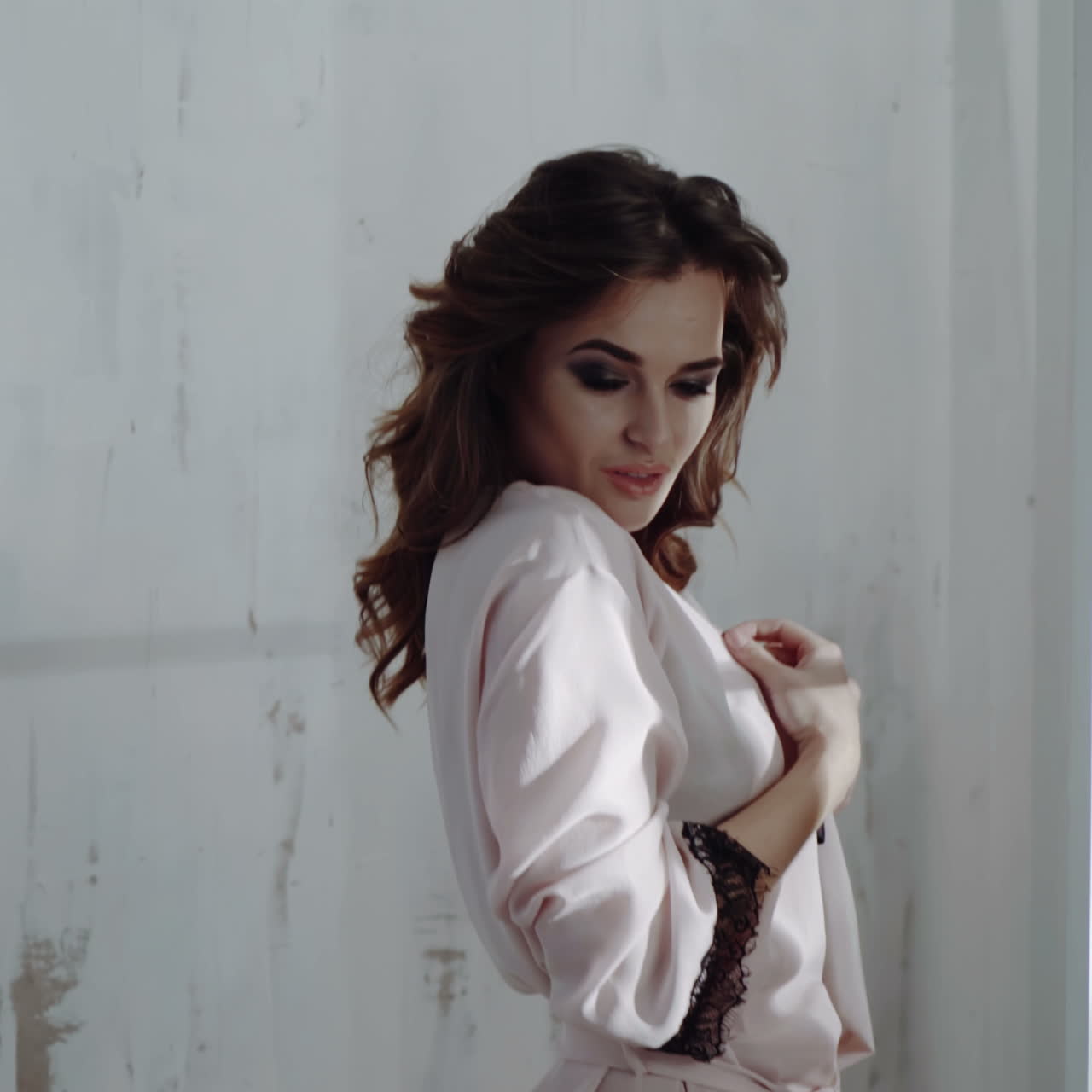 Sexy beautiful brunette woman posing in pink dressing gown. A girl with a thin thin body.