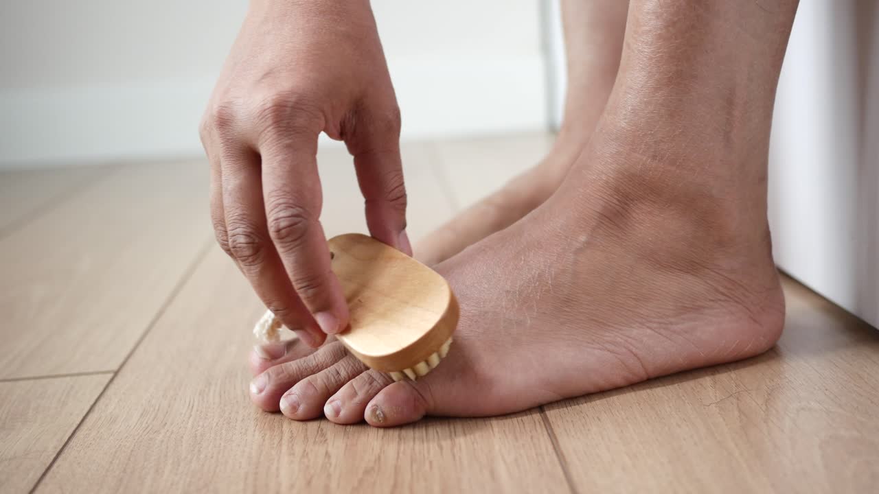 Persona che usa una spazzola per piedi per esfoliare i suoi piedi secchi