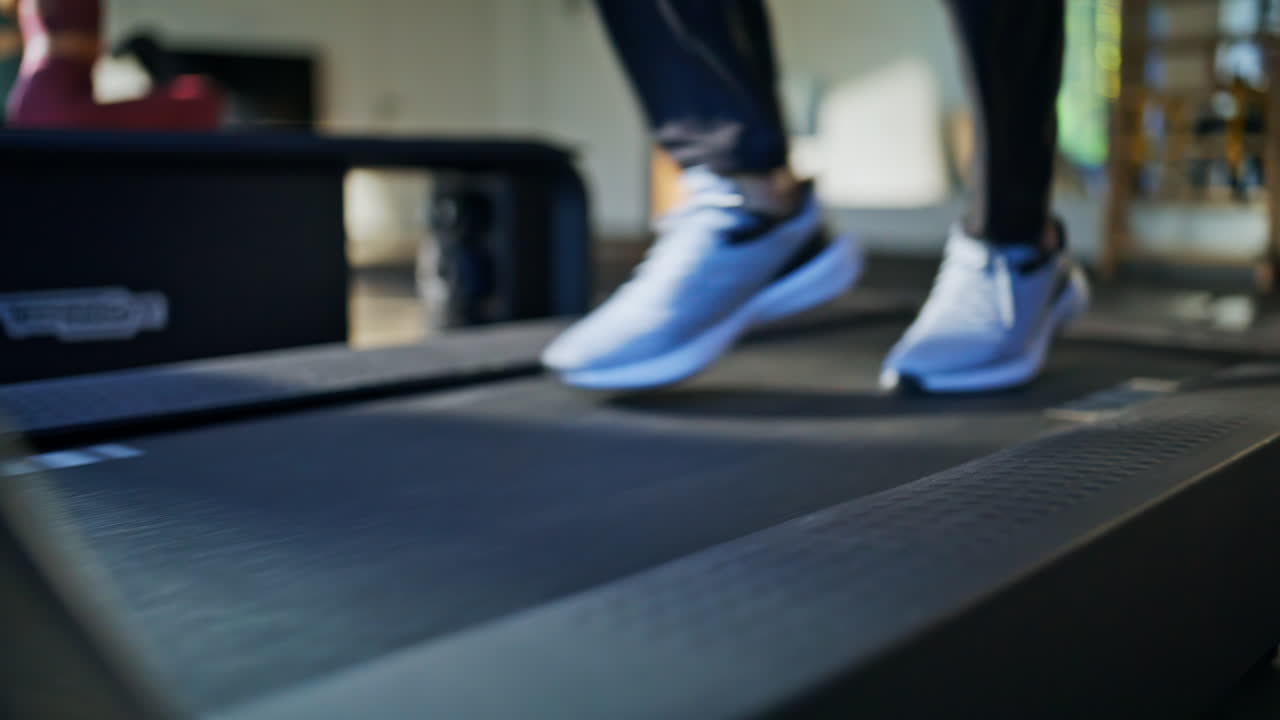 Pés de atleta correndo em esteira em close em clube esportivo. Pernas de homem não reconhecível
