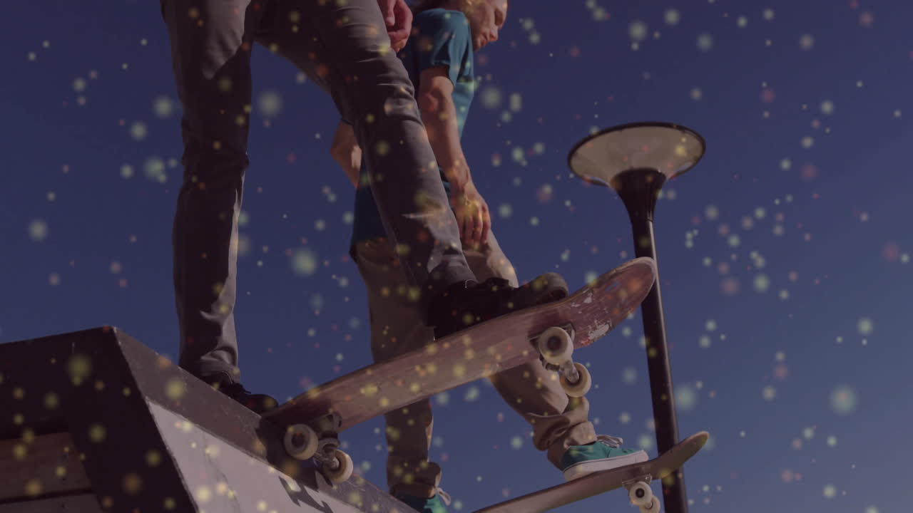 Two male skaters standing atop ramp under clear sky with floating light flecks for sports marketing