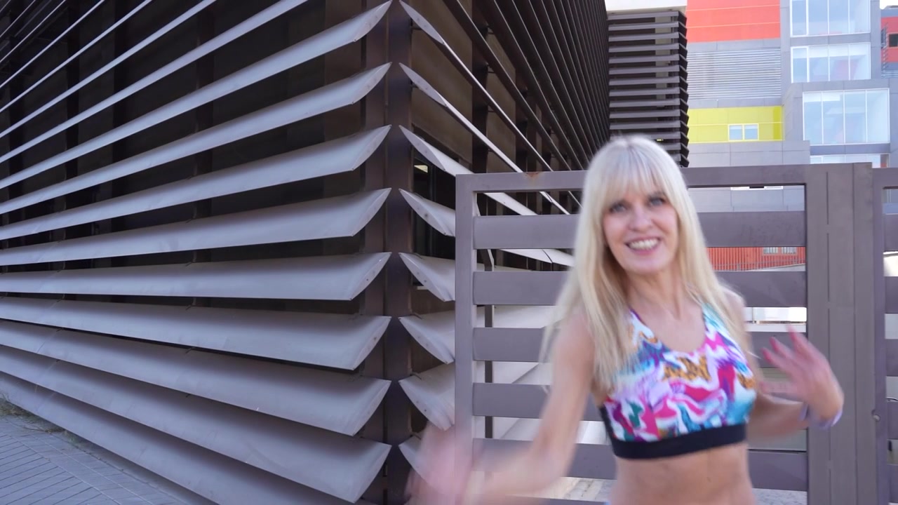 Una donna si sta allenando all'aperto in un vivace ambiente urbano, rappresentando uno stile di vita attivo.