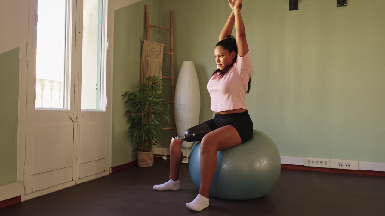Young Woman with Prosthetic Leg Stretching on Stability Ball