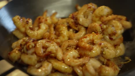 prawns being stirred and shaken inside wok with wooden spoon