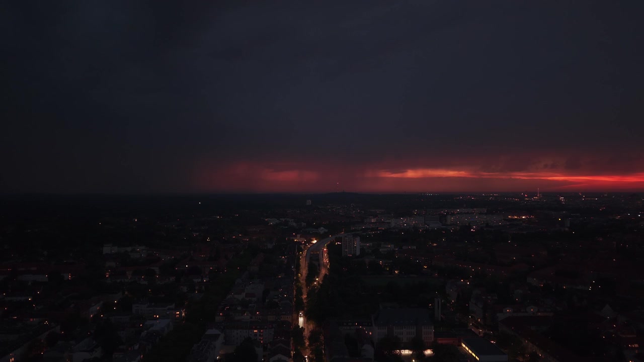 Tmavé mraky pokrývající panorama Berlína s pouličními lampami zářícími při západu slunce. Skvělý letecký pohled stoupajícího dronového panoramatu.