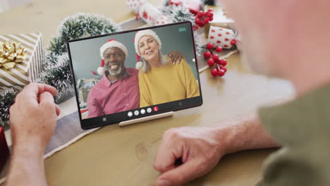un hombre caucásico de edad avanzada tiene una videoconferencia de navidad con una pareja de edad adulta.
