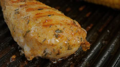 a deliciously seasoned chicken breast being pan fried in a hot iron grill skillet