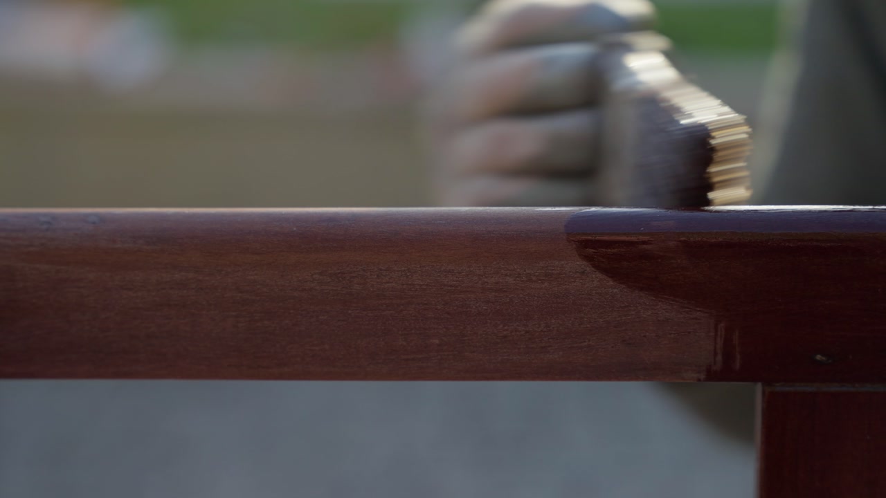 Macro shot of glossy varnished wooden chair frame rail with wet lacquer sheen outdoors