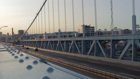 evening traffic driving across a suspension bridge at sunset in philadelphia, pennsylvania