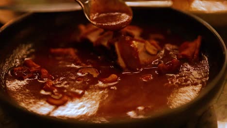 close-up of a curry being stirred in a pan, showcasing rich colors and textures under warm lighting