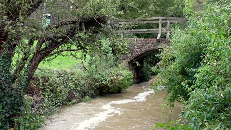 el río gwash que fluye a través del pueblo de braunston en rutland fuertemente hinchado después de fuertes lluvias