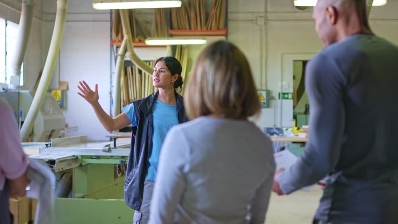Female Manager Explaining Project to Team in Woodworking Workshop