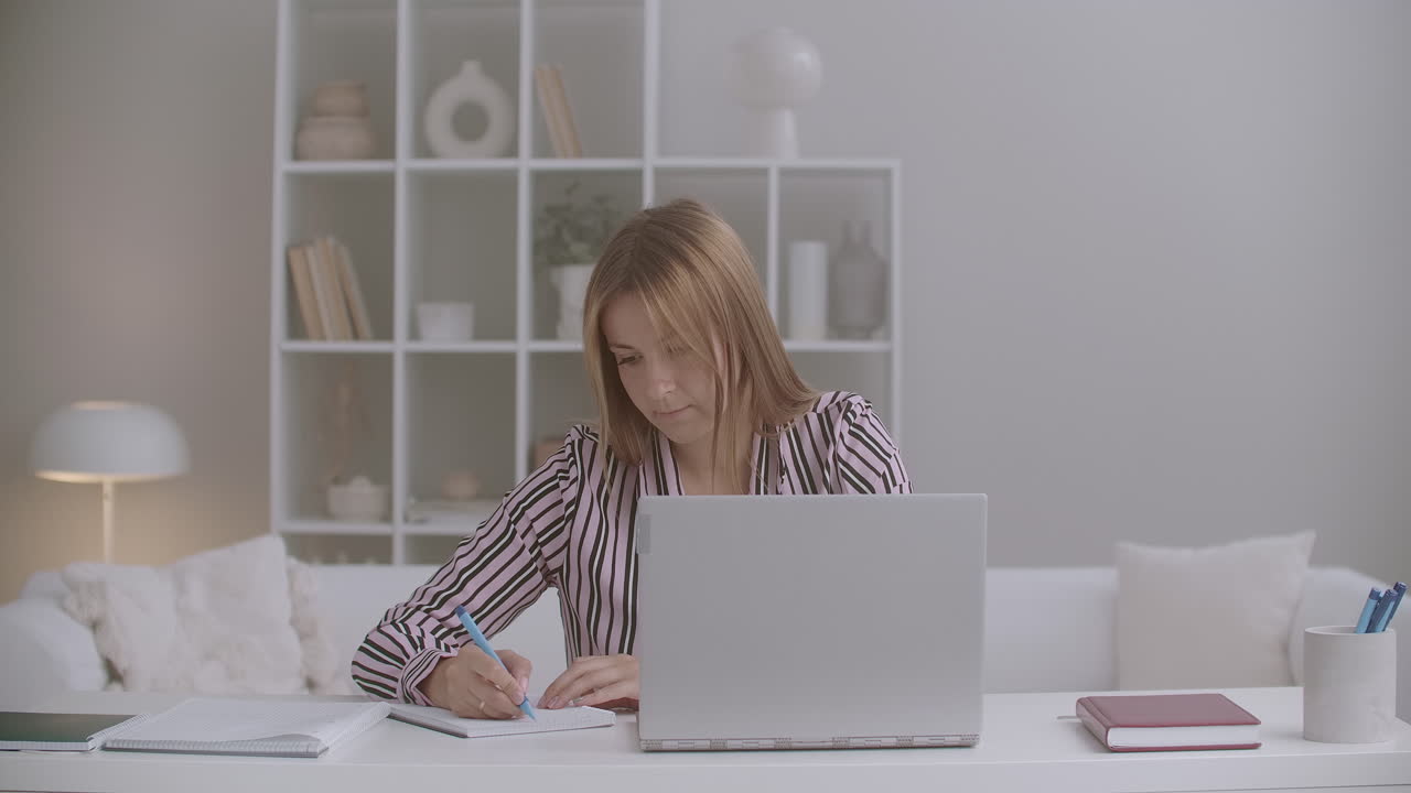 educación a distancia de una joven que está aprendiendo por internet usando una computadora portátil y escribiendo en un libro de texto quedándose en casa