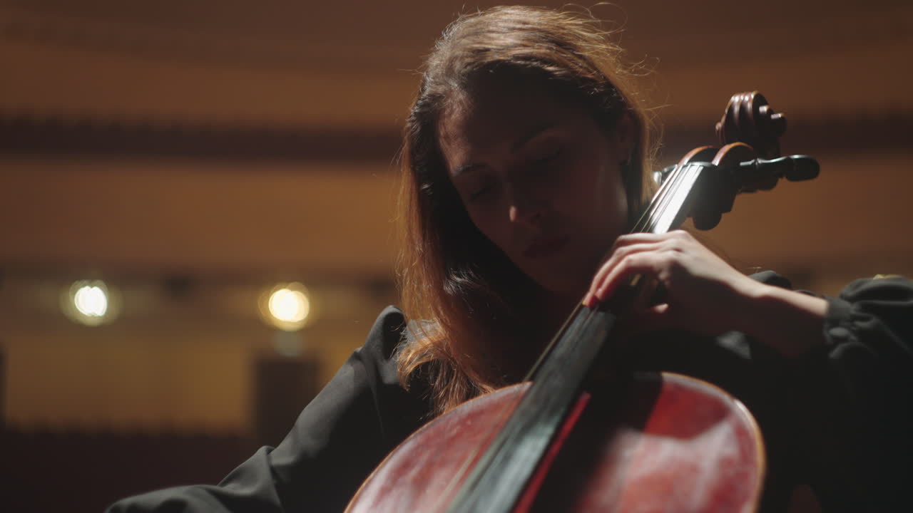 una hermosa mujer músico está tocando el violonchelo en la sala de música una violonchelista en la escena de la ópera