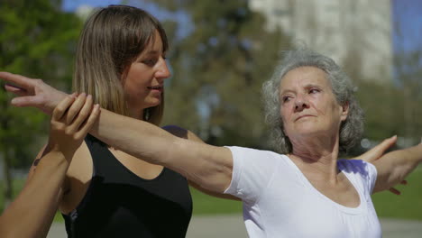 una joven entrenadora sonriente entrenando a una mujer mayor