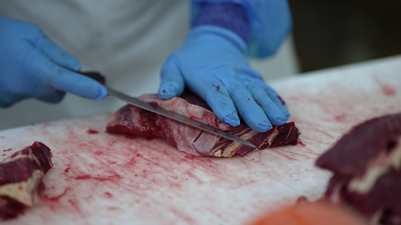Beef cut being separated by worker with a sharp knife at a meat processing plant, Close up shot