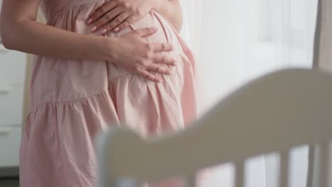 카메라는 배를 만지는 임산부의 손에 초점을 맞춥니다.