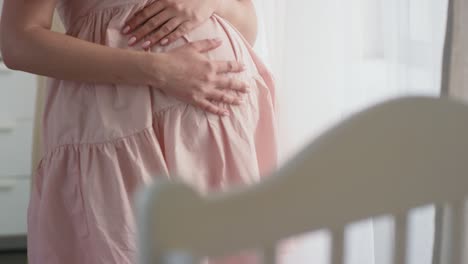 camera focuses on the hand of a pregnant woman touching her tummy