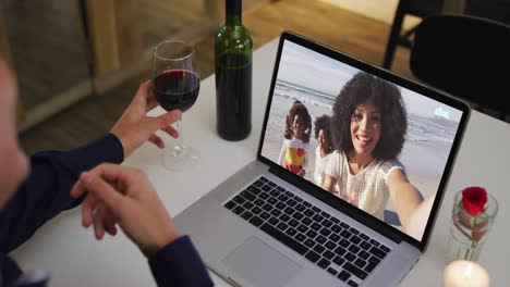 Mid-section-of-african-american-woman-drinking-wine-while-having-a-video-call-on-laptop-at-home