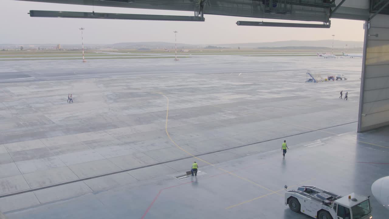 hangar del aeropuerto con trabajadores y pista vacía