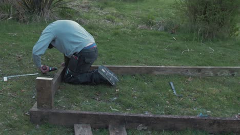 young man building raised garden bed with planks