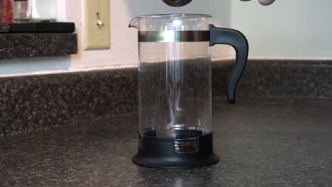 scooping coffee grounds into a french press coffee maker