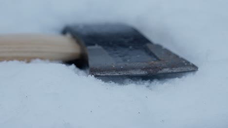 cerca empujar lentamente hacia el hacha que se encuentra en la nieve en polvo, macro