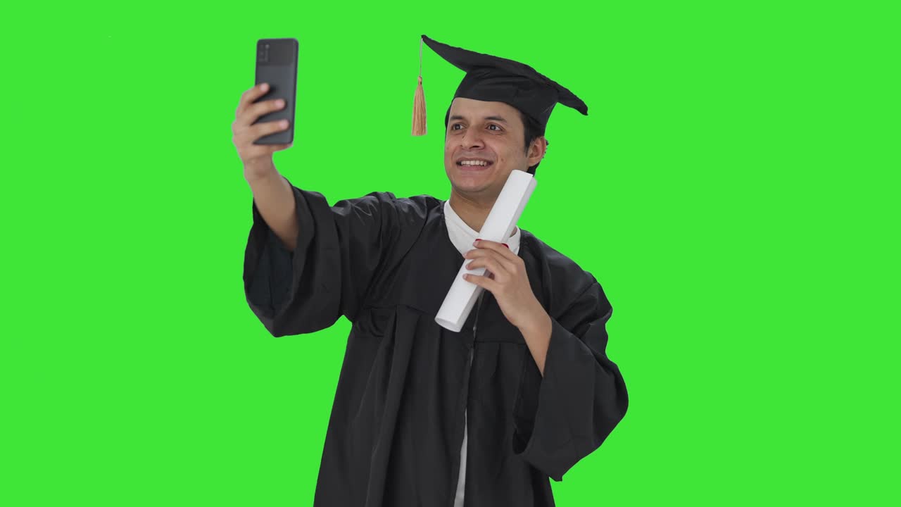 Felice studente universitario indiano neolaureato che si scatta selfie con la laurea Green screen