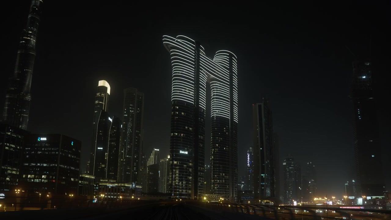 Vista notturna dal treno della metropolitana di Dubai che attraversa un paesaggio urbano moderno.