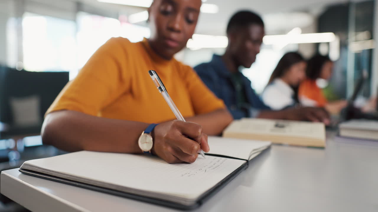 Fokuseret ung kvinde skriver i notesbog i et studiemiljø