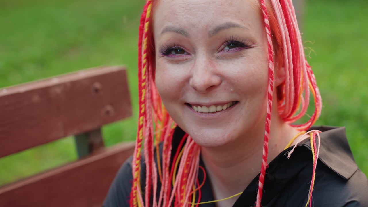 밝은 머리 색깔의 여성이 야외에서 윙크하는 모습, 생기 넘치는 땋은 머리의 여성이 공원 배경에서 장난기 넘치는 미소를 짓는 모습, 선명한 댕기 머리의 쾌활한 여성이 편안한 야외 순간에 장난스러운 윙크를 하는 모습