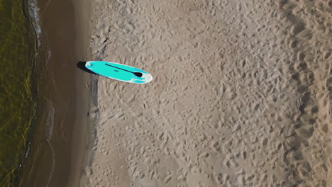 vista aérea de un solo stand up paddle board sup en la playa en el borde del agua