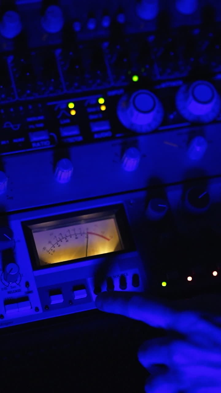 Equipment for professional music procession. Professional audio engineer's hand pressing the buttons on the stereo. Top view close up. Vertical video