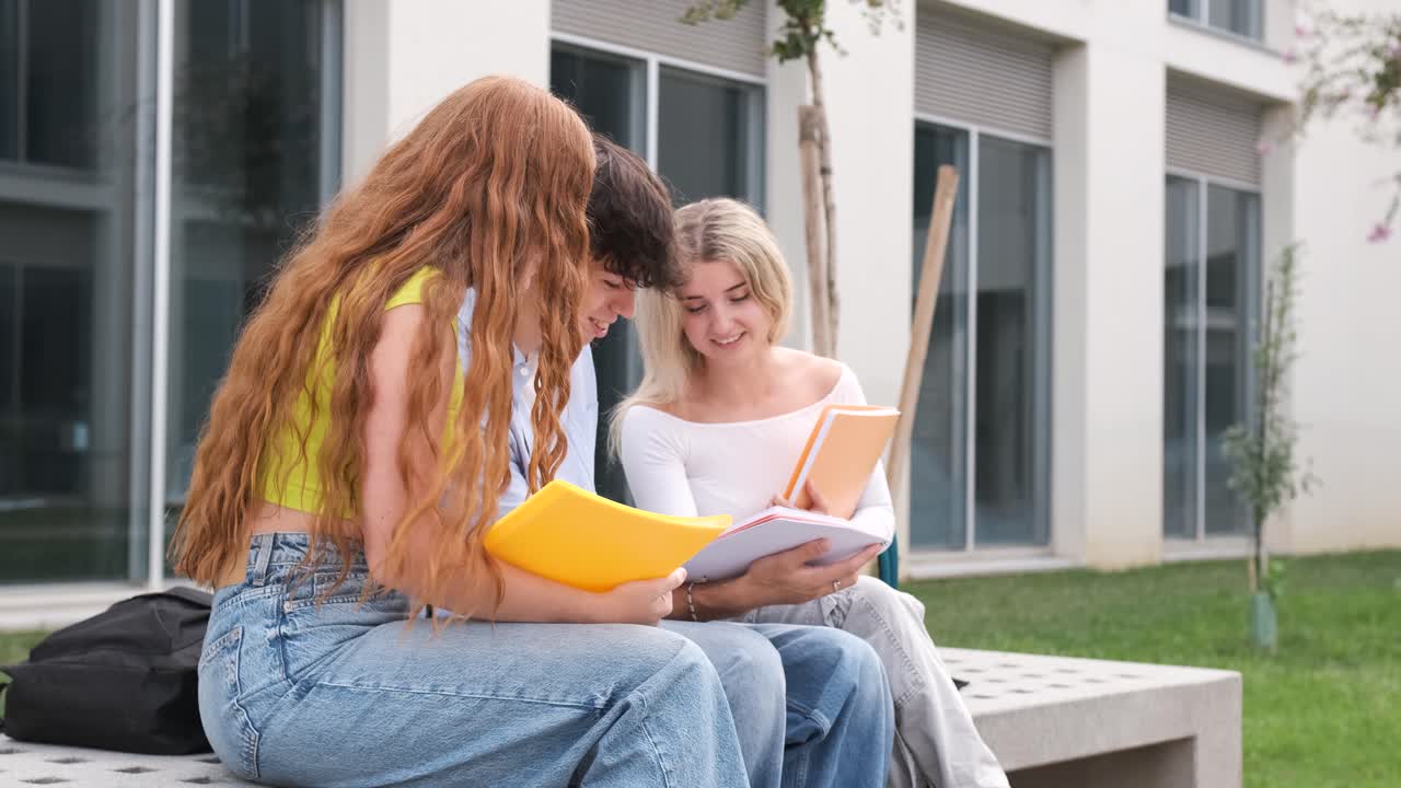 Amigos jóvenes leyendo un libro juntos en un banco en el campus universitario