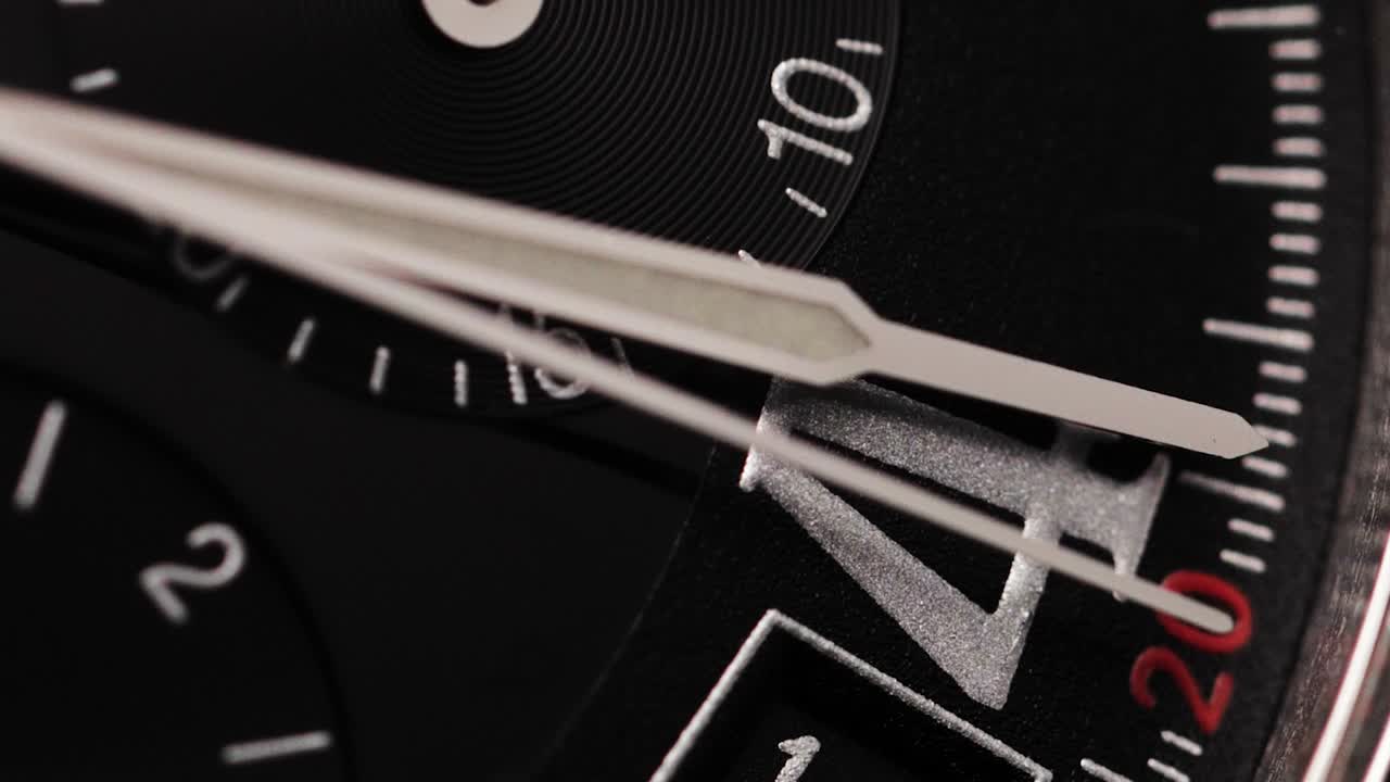Black watch dial with moving hands, emphasizing time passing, urgency and precision