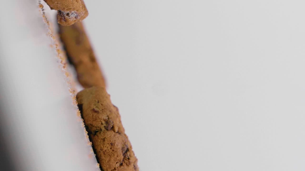 медленный вертикальный снимок падающих веганских печенья с шоколадом на белом фоне