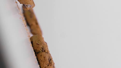 slow motion vertical shot of falling vegan cookies with chocolate against a white background