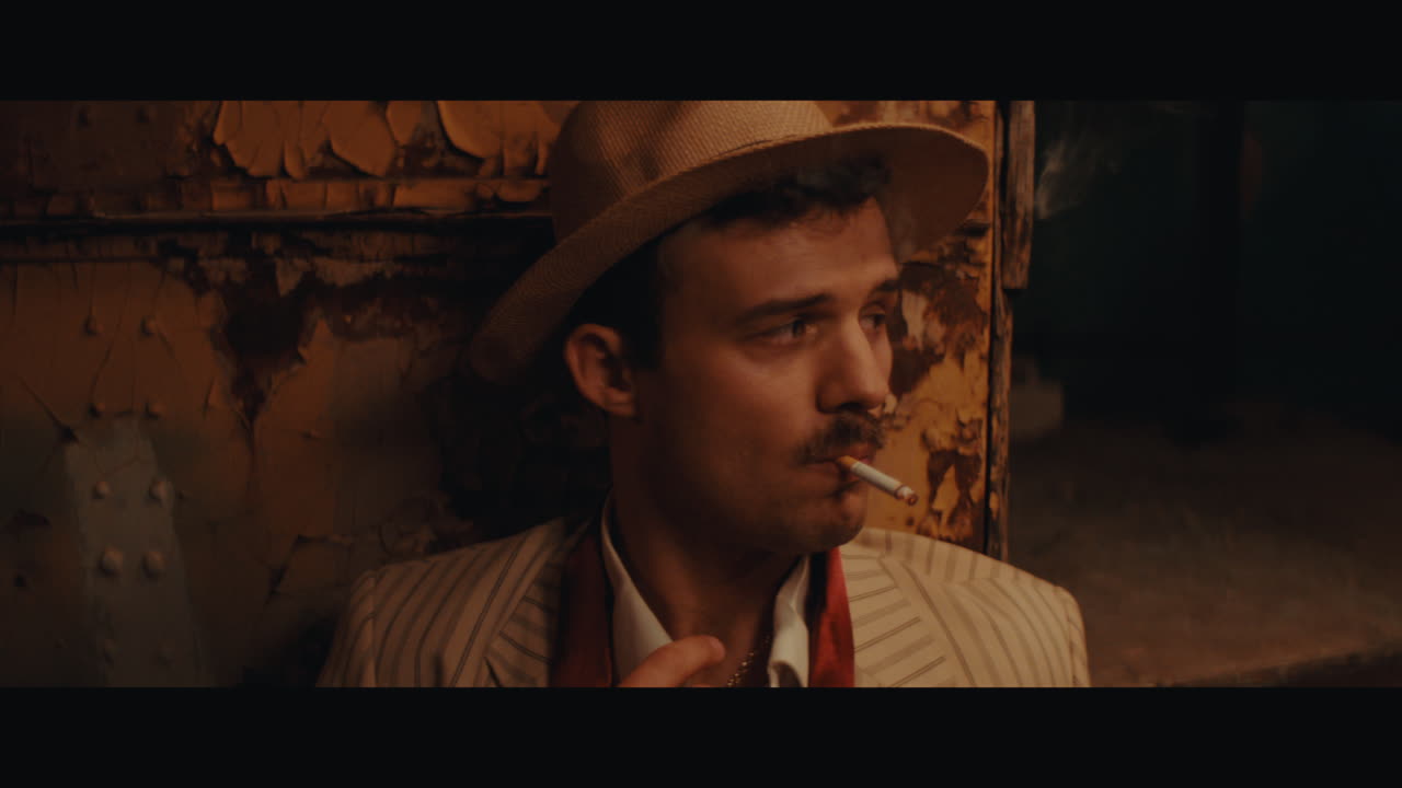 A man in hat smokes a cigarette in the circus camp