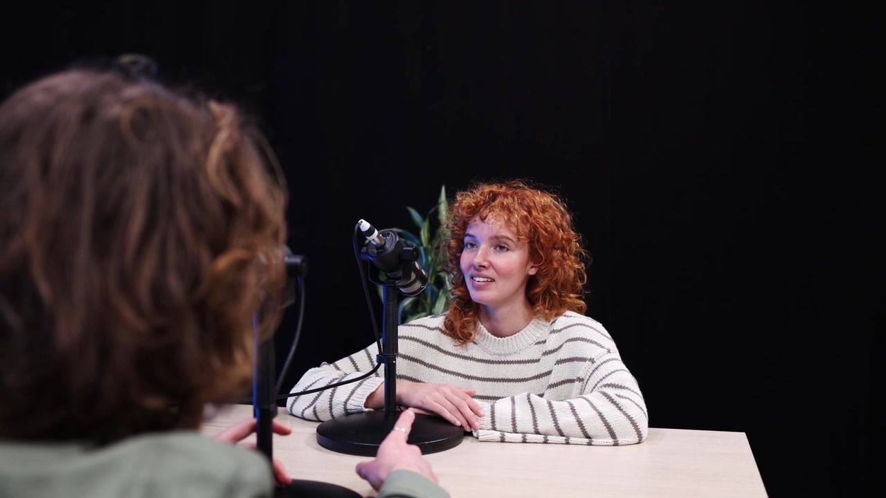 Jovem Mulher Falando ao Microfone Durante Entrevista de Podcast