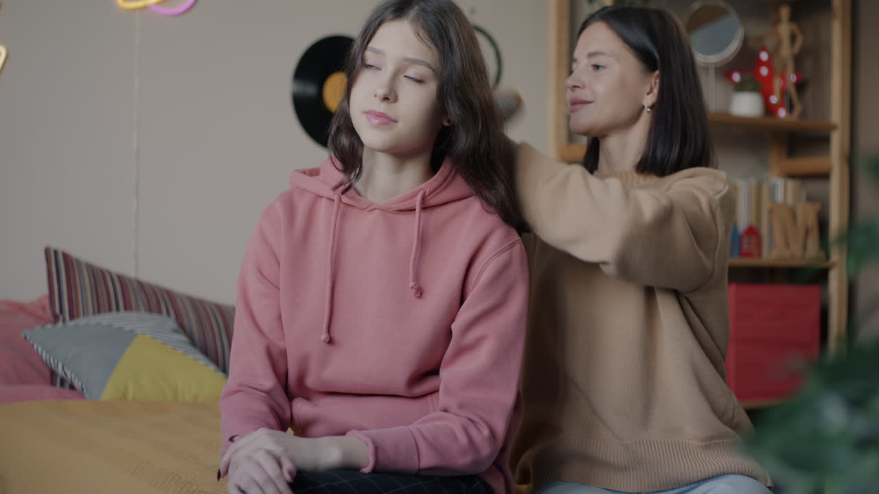 Mother brushing her daughter's hair in bedroom