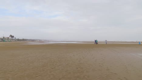 a long view of three tourists walking on the beach of barcelona, catalonia, spain