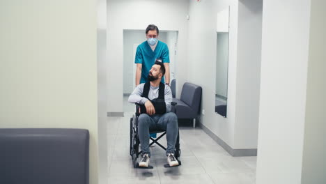 patient in wheelchair being assisted by medical staff in hospital corridor
