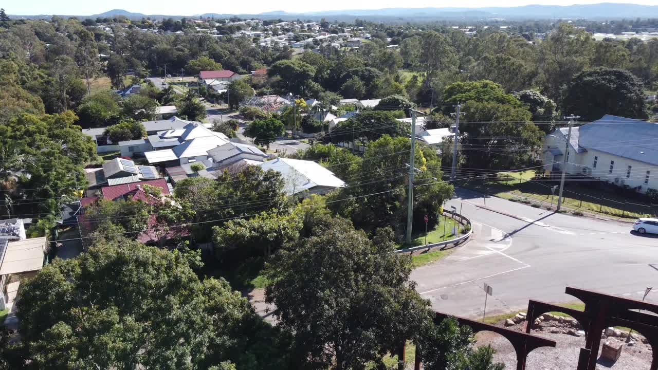 Drone descending into a park showing private residential area and local streets with cars passing by