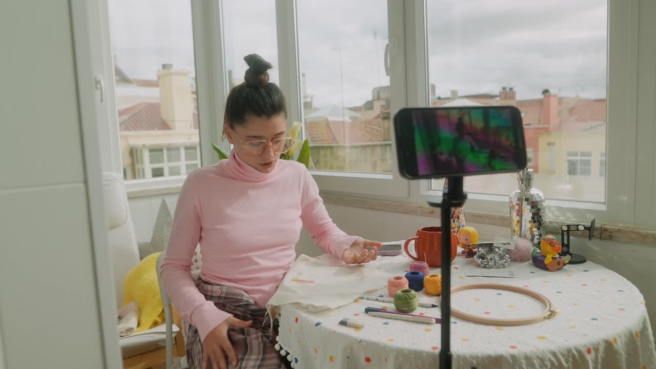 Ung kvinde optager en online broderi-tutorial derhjemme