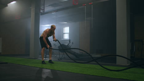 Hombre-De-Fitness-Haciendo-Ejercicio-Con-Cuerda-De-Batalla-Almacén-Abandonado.-Hombre-Duro-Trabajando-En-Un-Gimnasio-De-Entrenamiento-Cruzado-Hecho-Dentro-De-Una-Antigua-Fábrica.