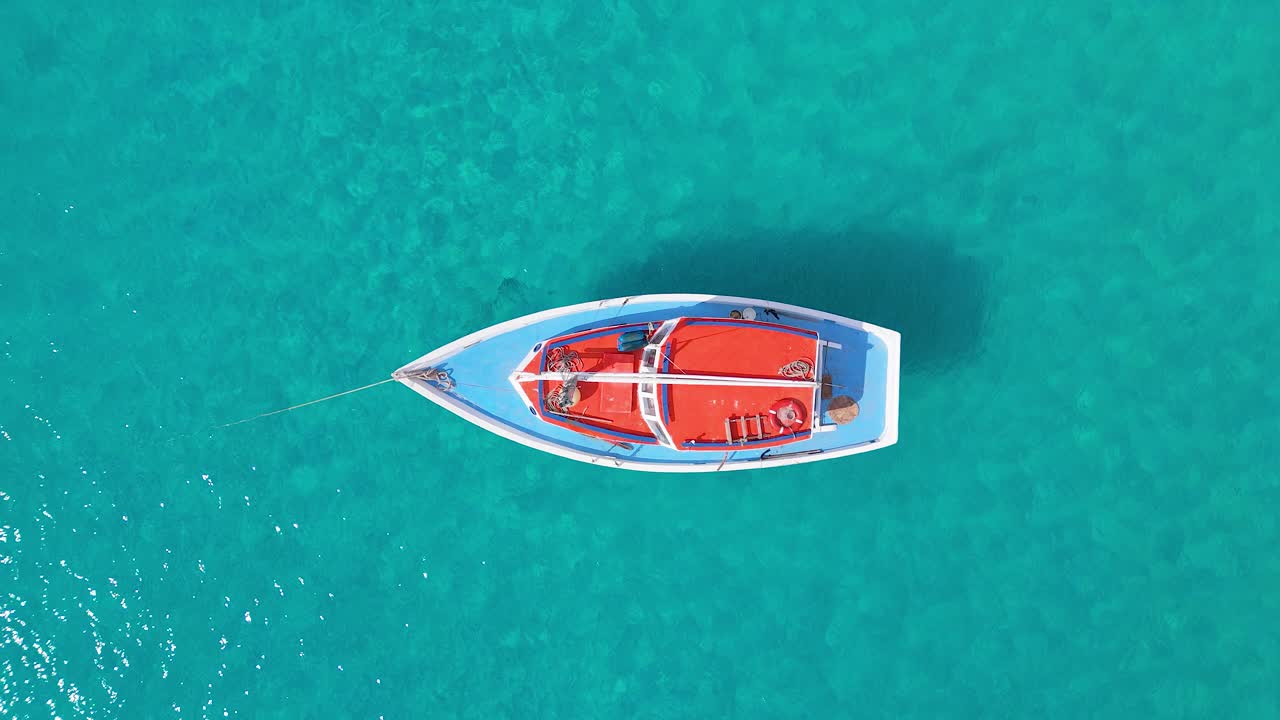 el velero tira contra el ancla mientras la sombra baila en el agua arenosa turquesa, el avión no tripulado arriba hacia abajo