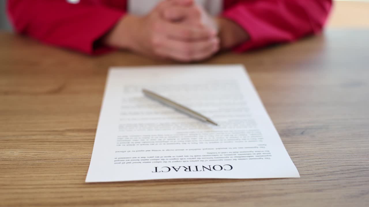 Female manager is sitting at office desk with contract paper and pen